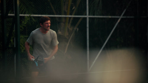 Male athlete playing tennis or padel on an outdoor court with focus and energy