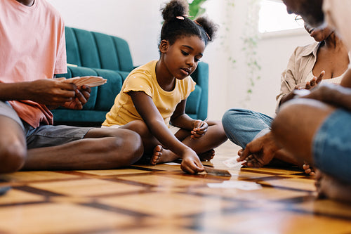 Family playing a card game on the floor in their living room