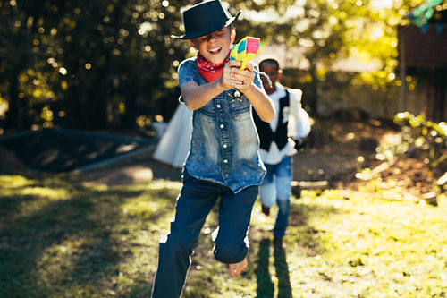 Young boys in backyard playing with water pistols