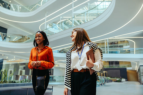 Two coworkers walking through a state-of-the-art office engaged in conversation