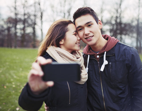 Affectionate young couple taking pictures using a smart phone