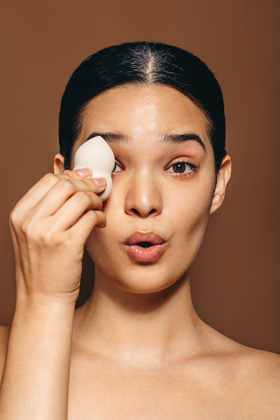 Fun skincare routine: Woman holding a makeup sponge in a studio