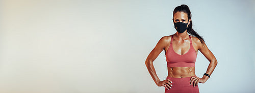 Muscular female in sportswear and face mask