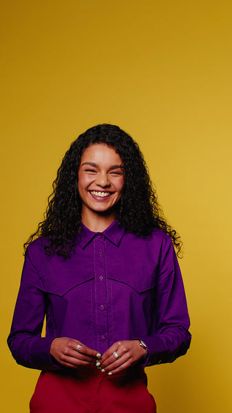 Young woman laughs on yellow background