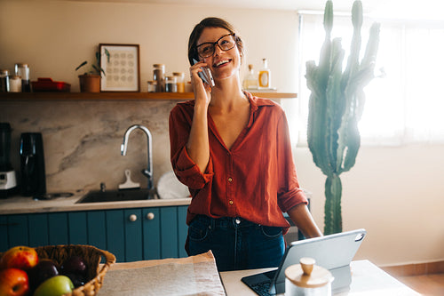 Woman on phone in cozy kitchen with laptop