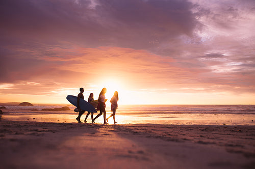 Silhouette of people walking on beach at sunset
