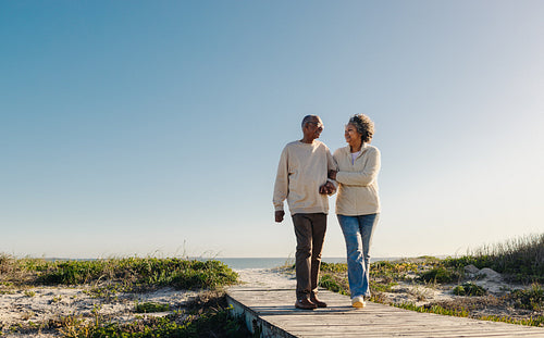 Romantic senior couple walking down a foot bridge at the beach