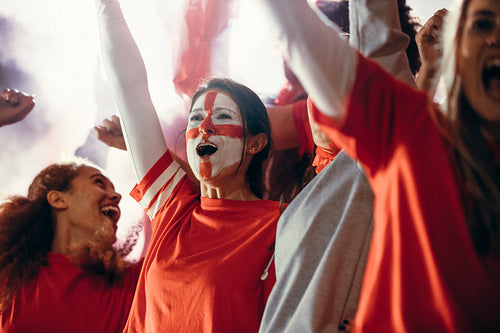 Devoted soccer fans in stadium cheering a goal