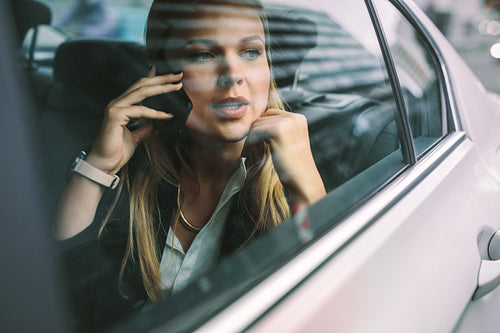 Businesswoman making phone call in taxi