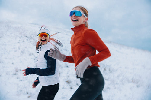 Women running together in winter snow during outdoor fitness training