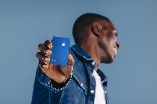 Happy black man holds his credit card towards the camera, recommending the use of mobile payments and electronic banking