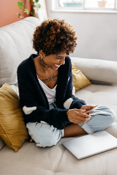 Smiling young woman enjoying time with smartphone at home