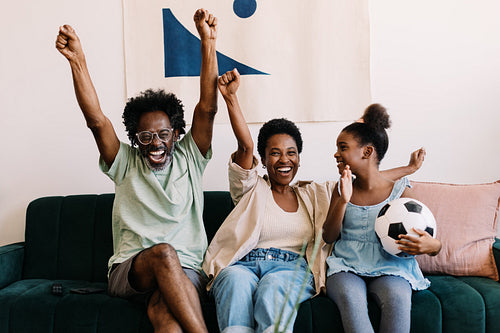 Black family celebrating and enjoying a football game at home