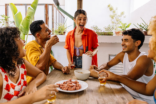 Brazilian friends laughing and drinking together at summer barbecue