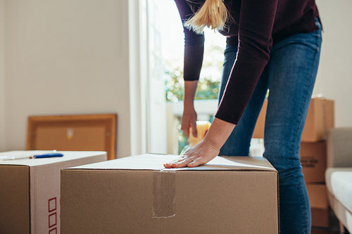 Woman sealing a packing box using adhesive tape