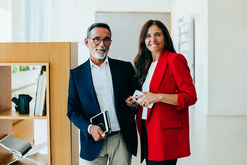 Two senior managers posing confidently in an office environment