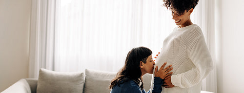 Woman kissing her wife's pregnant belly