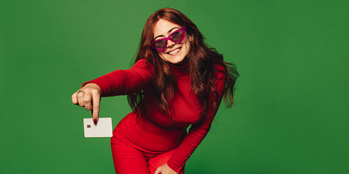 Happy woman holding credit card for contactless payment on green background