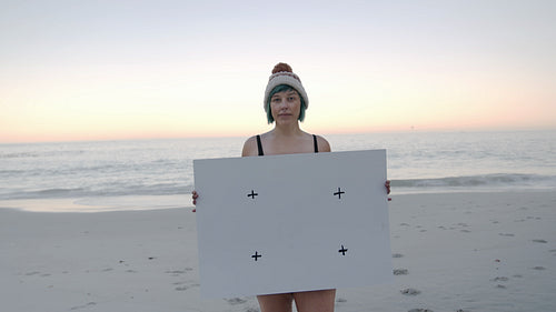 Mature woman with empty billboard on the beach