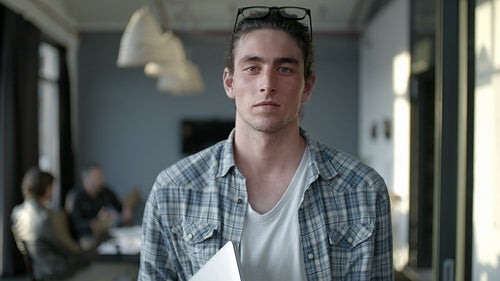 Smiling man in office with staff meeting in the back