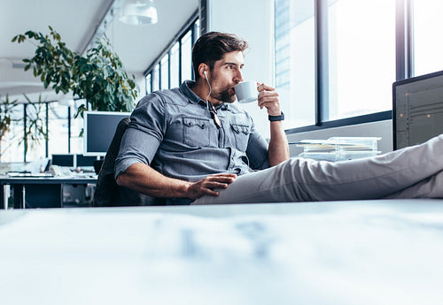 Young man drinking coffee during break in office