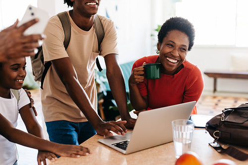 Family using a laptop with smiles and laughter in the morning at home