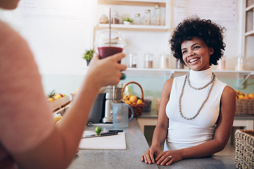 Juice bar owner with customer holding a glass of juice
