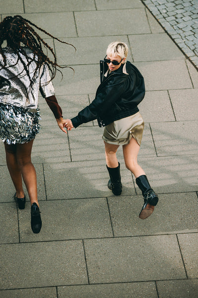 Running hand in hand: friends racing down a city street