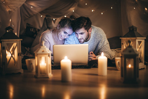 Couple lying on bed looking at a laptop