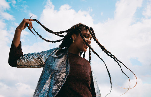 Braids in motion: woman tossing her hair against a bright blue sky