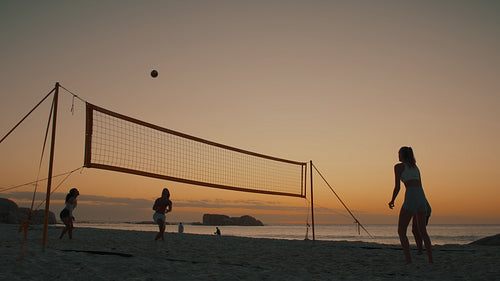 Summer games: Four silhouetted beach volleyball players on the court at sunset