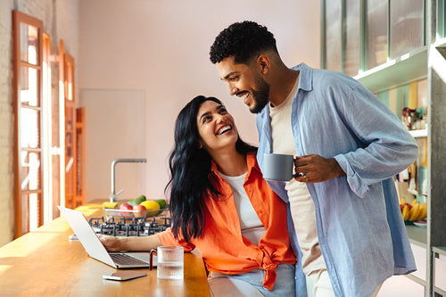 Happy couple enjoying morning coffee together in a modern kitchen setting.