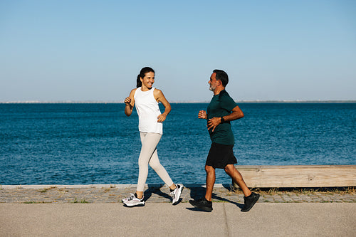 Senior couple jogging near the ocean on a sunny morning