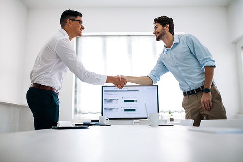 Business partners shaking hands in office