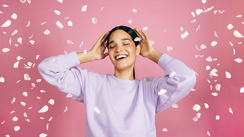 Confetti celebration of self, woman stands under falling confetti in a studio