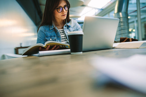 Female student studying at university canteen.