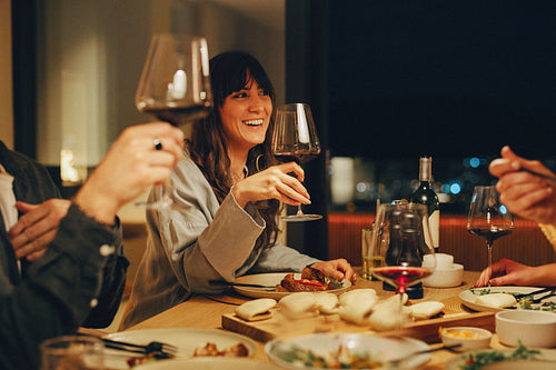 Friends enjoying a cozy dinner with wine and laughter at night