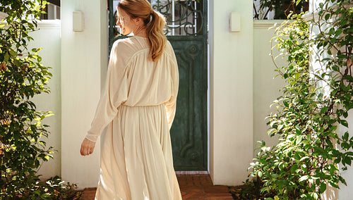 Rearview of a young woman standing outside a holiday home