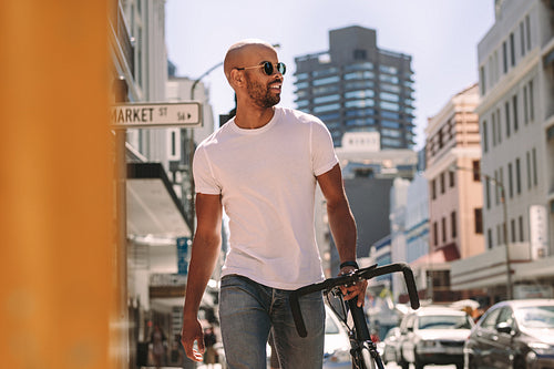 Handsome man in casuals walking outdoors with bicycle