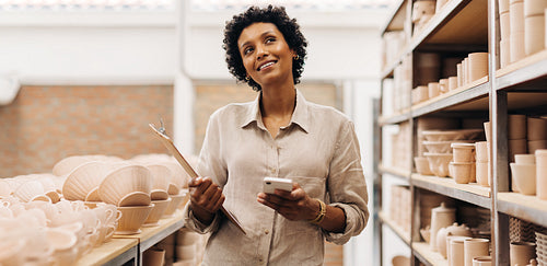 Cheerful female ceramist contemplating new ideas for her shop