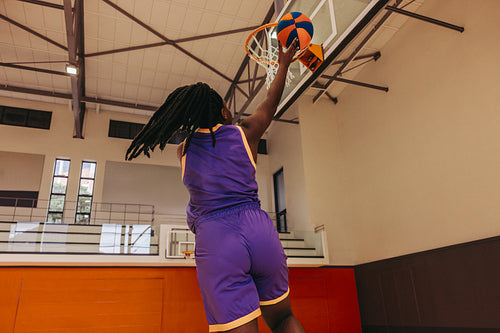 Athlete dunking basketball in gym displaying sports action and athleticism skills