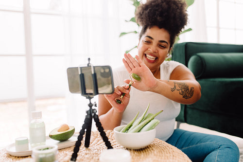 Woman vlogging how to use jade roller on skin