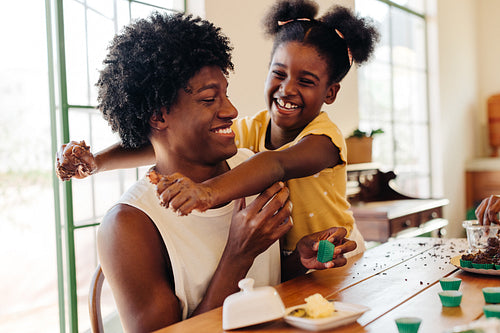 Young sister playfully hugging her brother while making brigadeiro in a Brazilian home