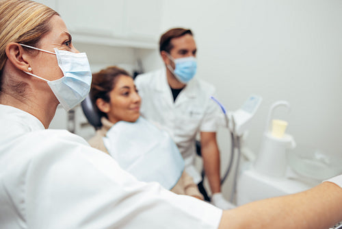 Female dentist with face mask showing x-ray to patient