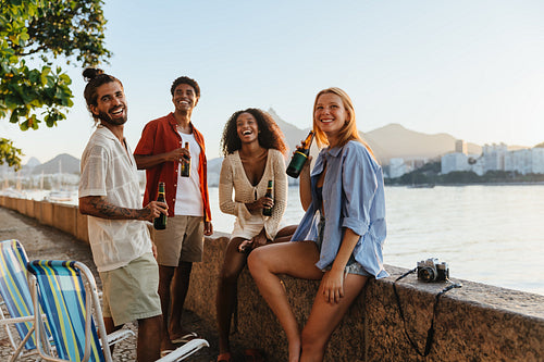 Group of friends enjoying drinks by the waterfront at sunset