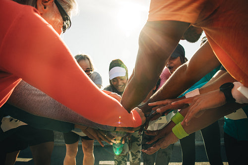 Group of runners huddling with hands united before a race