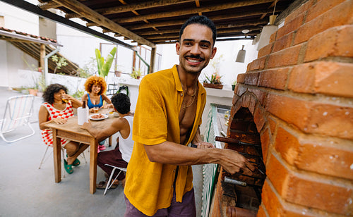 Smiling man grilling at a summer gathering with friends in Rio de Janeiro