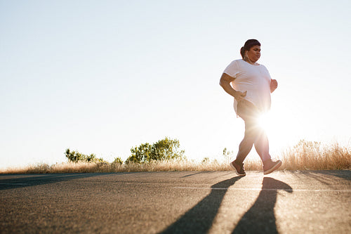 Overweight woman jogging on the highway