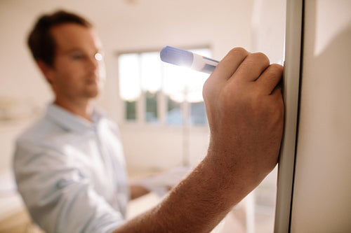 Man writing on whiteboard with marker pen