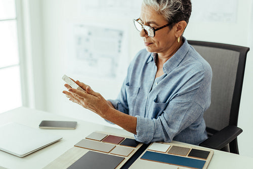 Senior interior designer sits at her desk carefully reviewing colour swatches for a project